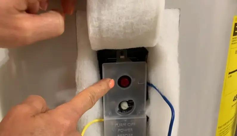 The red reset button on the panel of an electric water heater